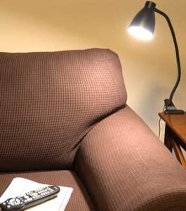 The BOHON LED Clamp On Desk Light attached to an end table directing light toward a magazine on the couch